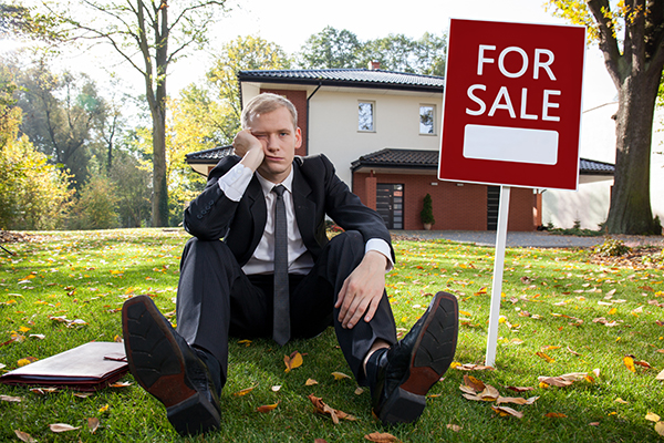 burnt out real estate professional by for sale sign