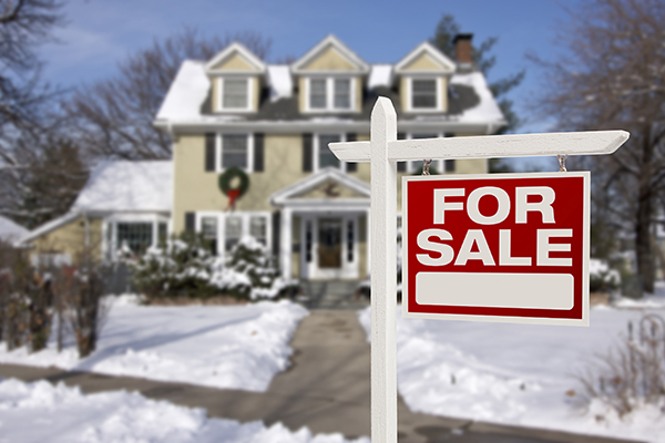 For sale sign placed in front of home in winter