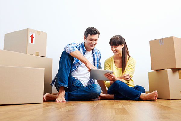 Couple Surrounded by Boxes Looking for Professional Movers on iPad